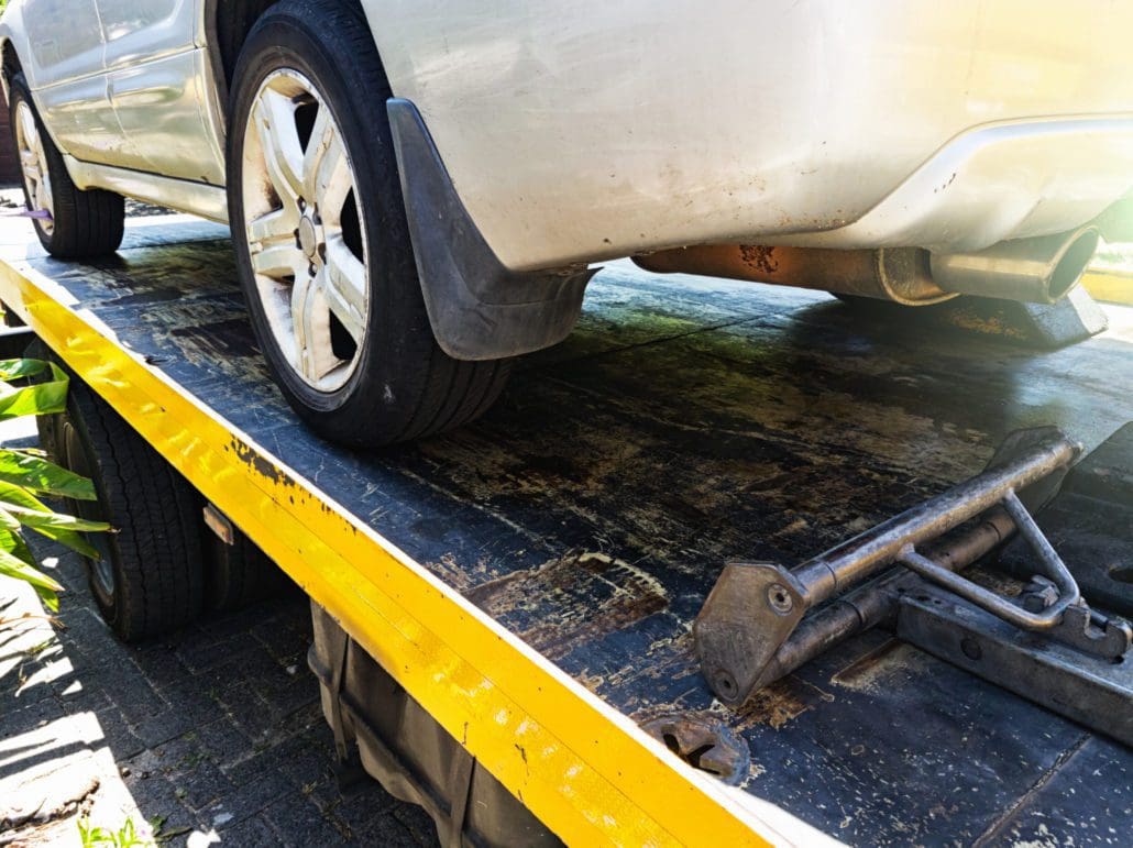 car loaded onto a tow truck and being anchored to it for safety.