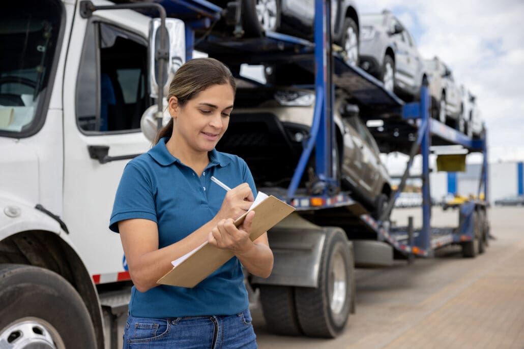 Latin American woman working at a distribution warehouse and supervising the shipping of cars to the dealerships
